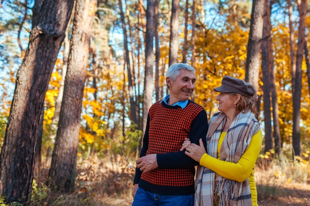 Passeggiata autunnale. Coppie senior che camminano nel parco di caduta. Uomo e donna felici che parlano e che si rilassano all'aperto