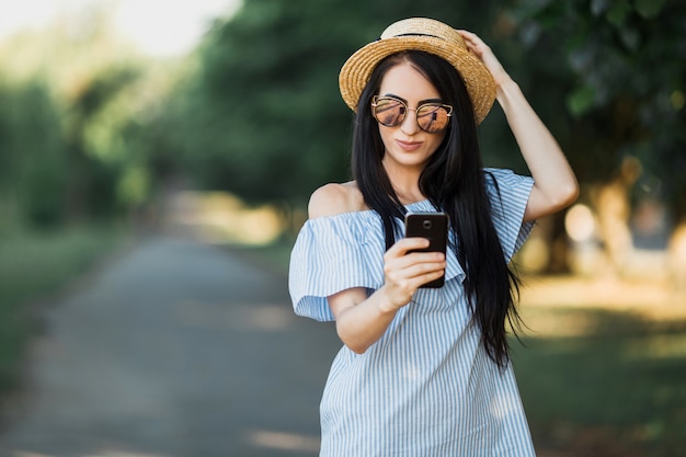 Passeggiata della donna nel parco e nel telefono usando.