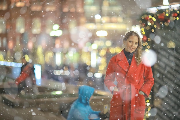 Passeggiata di Natale in città / ragazza adulta cammina nella città di notte in una notte festiva, le luci della città sono il nuovo anno