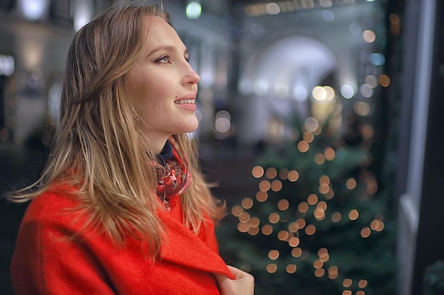 Passeggiata di Natale in città / ragazza adulta cammina nella città di notte in una notte festiva, le luci della città sono il nuovo anno