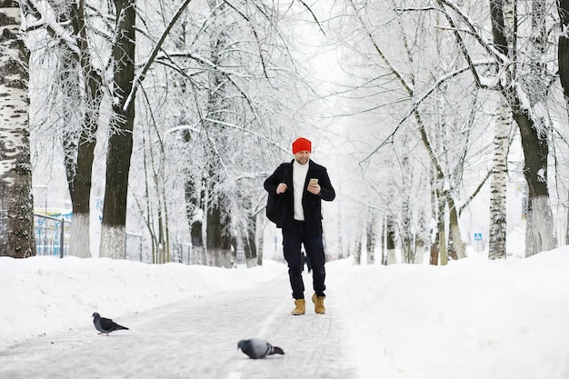 Passeggiata invernale con ombrelloL'uomo con un cappotto con ombrello cammina sullo sfondo del paesaggio invernale Vista invernale