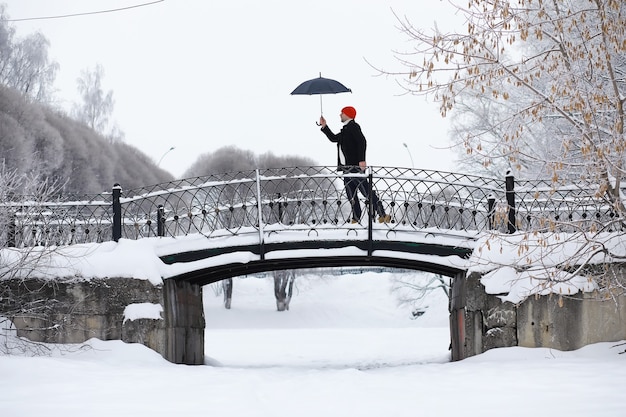 Passeggiata invernale con un ombrello. Uomo con un cappotto con un ombrello, cammina sullo sfondo del paesaggio invernale, vista invernale