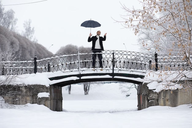 Passeggiata invernale con un ombrello. Uomo con un cappotto con un ombrello, cammina sullo sfondo del paesaggio invernale, vista invernale