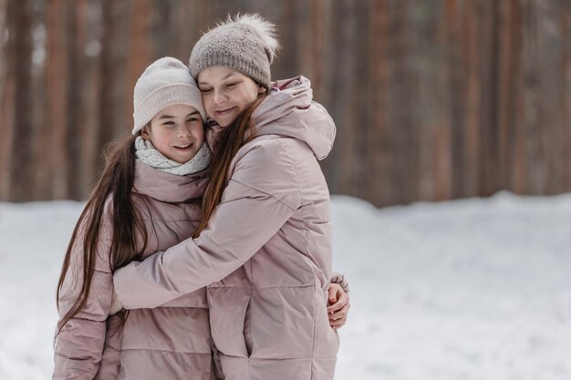 Passeggiata invernale in famiglia nella foresta Madre e figlia si divertono in inverno nella foresta con tempo soleggiato e gelido Un abbraccio di madre