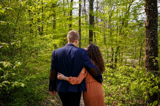 Passeggiata romantica di una giovane coppia in una foresta verde, caldo clima primaverile. Ragazzo e ragazza che si abbracciano nella natura