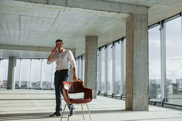 Passeggiate e colloqui Il giovane in abbigliamento formale sta lavorando al chiuso per la costruzione