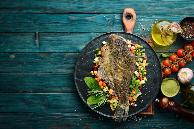 Passera di pesce al forno con verdure su un piatto di pietra nera Frutti di mare Vista dall'alto Spazio libero per il testo