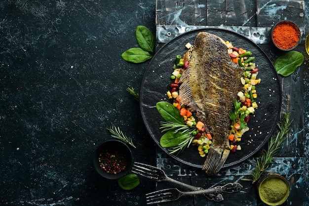 Passera di pesce al forno con verdure su un piatto di pietra nera Frutti di mare Vista dall'alto Spazio libero per il testo