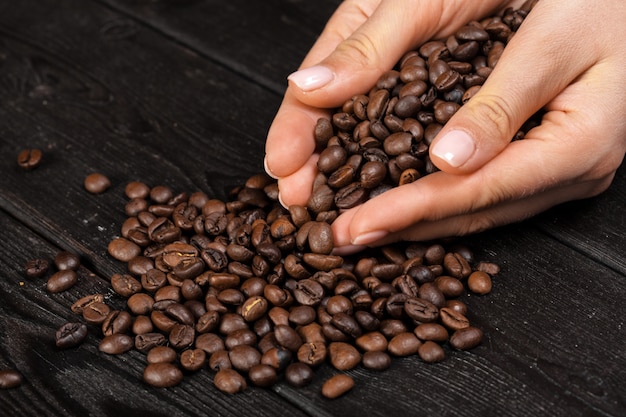 Passi il caffè della tenuta con il chicco di caffè sulla tavola di legno