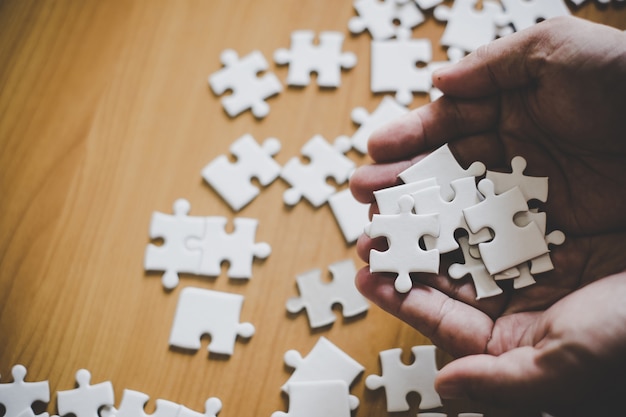 Passi la tenuta del pezzo di puzzle in bianco con il fondo di legno della tavola.