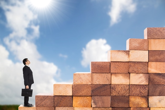 Passi verso il successo, l'uomo d'affari inizia a salire le scale di legno per andare avanti con la sua attività di successo.