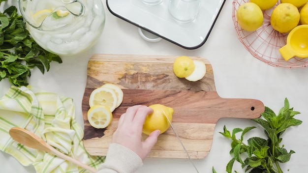 Passo dopo passo. Affettare il limone biologico sul tagliere di legno.