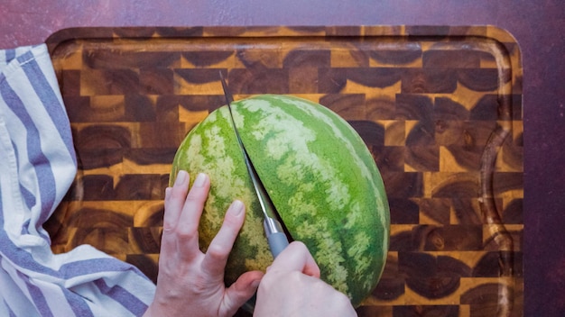 Passo dopo passo. Affettare il melone rosso su un tagliere di legno.