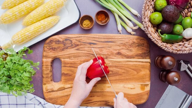 Passo dopo passo. Affettare il peperone rosso su un tagliere di legno.