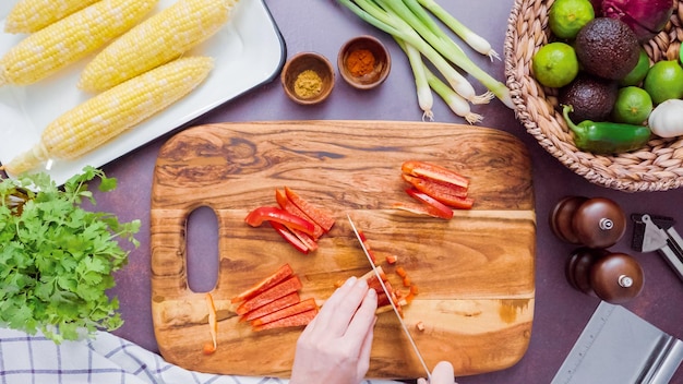 Passo dopo passo. Affettare il peperone rosso su un tagliere di legno.