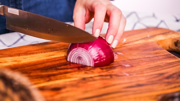 Passo dopo passo. Affettare la cipolla viola su un tagliere di legno.