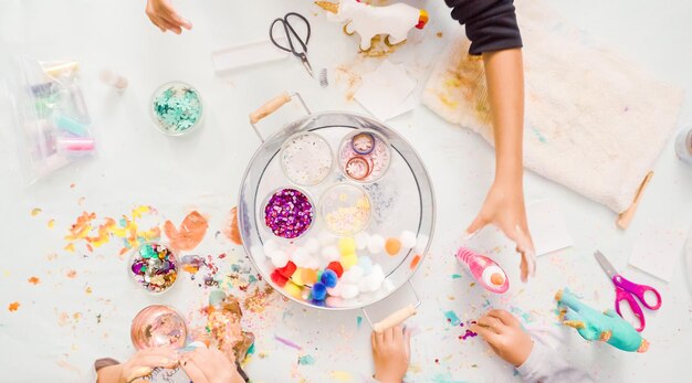 Passo dopo passo. Bambine che decorano unicorno di cartapesta con glitter e fiori di carta.