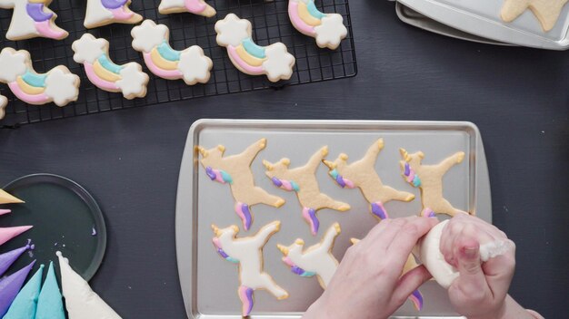 Passo dopo passo. Disposizione piatta. Decorare i biscotti di zucchero di unicorno con glassa reale sulla teglia.