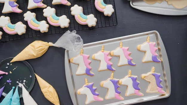 Passo dopo passo. Disposizione piatta. Decorare i biscotti di zucchero di unicorno con glassa reale sulla teglia.