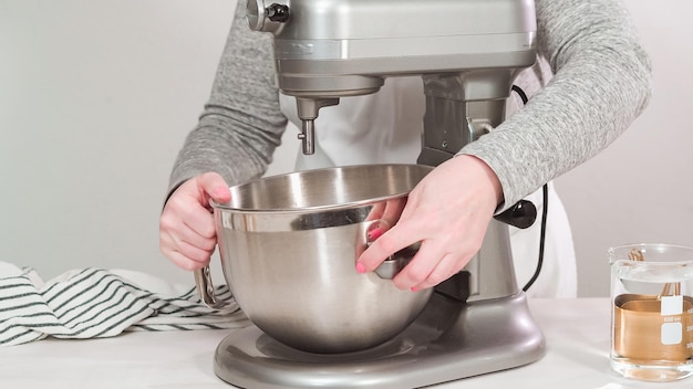 Passo dopo passo. Disposizione piatta. Mescolare la ghiaccia reale nello sbattitore elettrico da cucina per i biscotti di Pasqua.