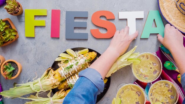 Passo dopo passo. Fiesta segno sul tavolo con mais messicano sulla pannocchia Elote.