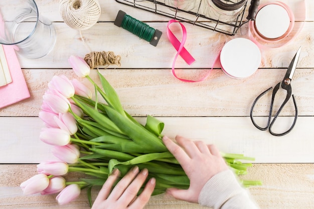 Passo dopo passo. Fiorista che avvolge i tulipani rosa nel bouquet.