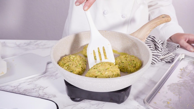 Passo dopo passo. Friggere le torte di zucchine in olio d'oliva su una piccola padella.