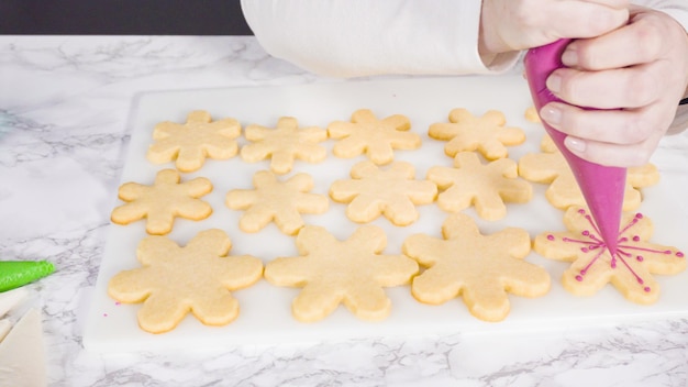 Passo dopo passo. Glassa i biscotti di zucchero a forma di fiocco di neve con glassa reale rosa.