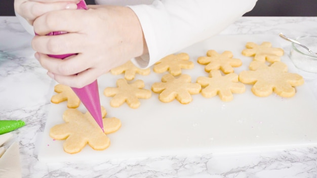 Passo dopo passo. Glassa i biscotti di zucchero a forma di fiocco di neve con glassa reale rosa.