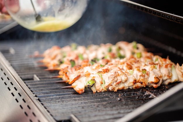 Passo dopo passo. Grigliare yakitori di pollo su spiedini di bambù su una griglia a gas all'aperto.