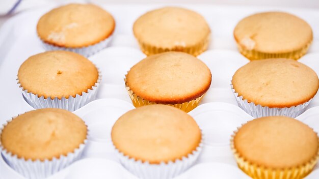 Passo dopo passo. Il pasticcere che pipa la glassa di crema al burro sui cupcakes di unicorno per la festa di compleanno della bambina.