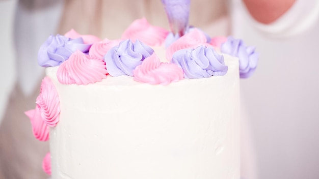 Passo dopo passo. Il pasticcere piping glassa di crema al burro sulla torta di unicorno per la festa di compleanno della bambina.