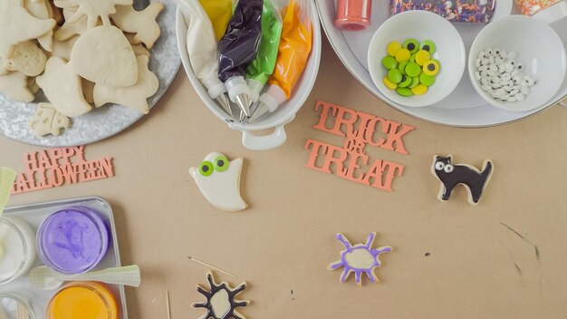 Passo dopo passo. Madre e figlia che decorano i biscotti di zucchero di Halloween con glassa reale colorata.