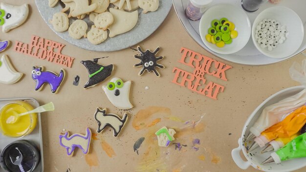 Passo dopo passo. Madre e figlia che decorano i biscotti di zucchero di Halloween con glassa reale colorata.