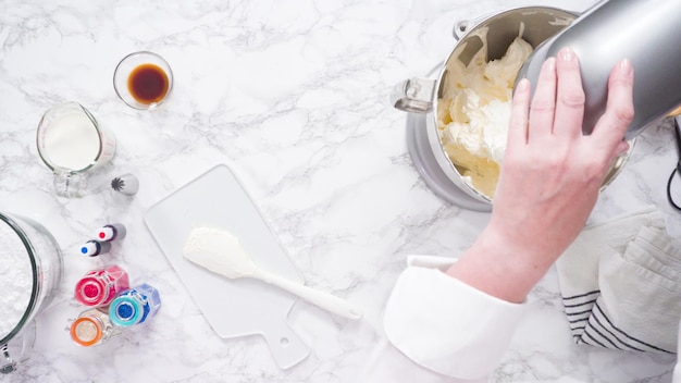 Passo dopo passo. Mescolare gli ingredienti in una planetaria da cucina per fare la glassa alla crema di burro.