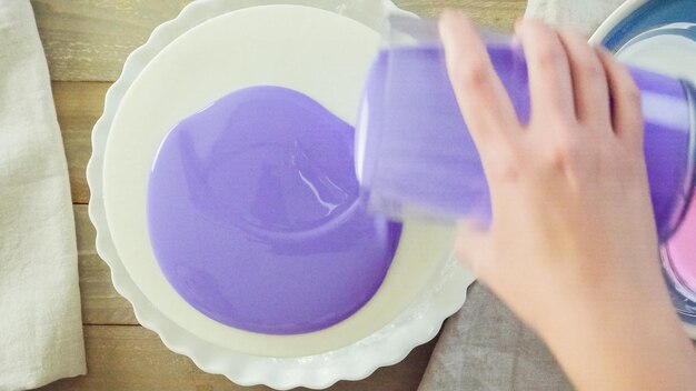 Passo dopo passo. Pastre shef che prepara una torta di mousse con glassa a specchio viola e decorata con fiori rosa cioccolato.