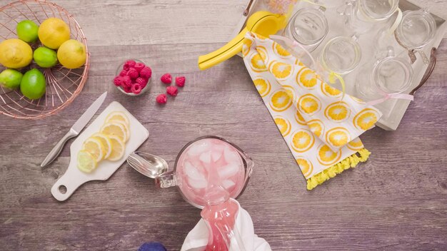 Passo dopo passo. Preparare la limonata al lampone con limoni freschi e lamponi in barattoli di vetro da bere.
