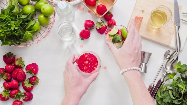 Passo dopo passo. Preparazione del mojito alla fragola da fragole fresche biologiche.