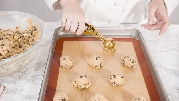 Passo dopo passo. Raccogliere i biscotti con gocce di cioccolato fatti in casa con un cucchiaio di pasta di metallo sulla teglia.