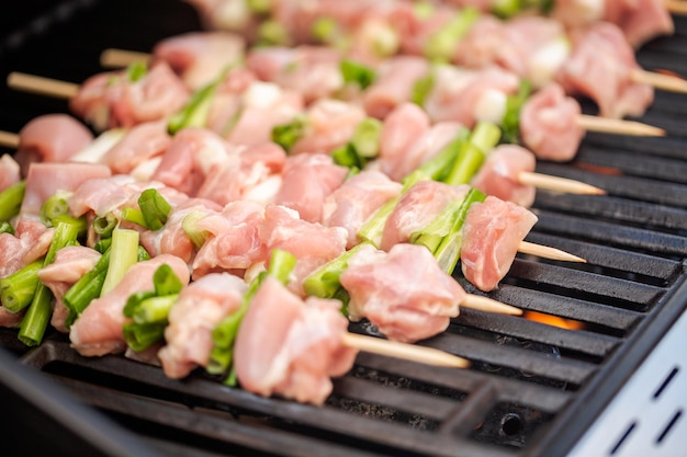 Passo dopo passo. Spiedini di yakitori di pollo crudo sulla griglia a gas all'aperto.