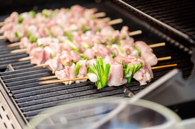 Passo dopo passo. Spiedini di yakitori di pollo crudo sulla griglia a gas all'aperto.