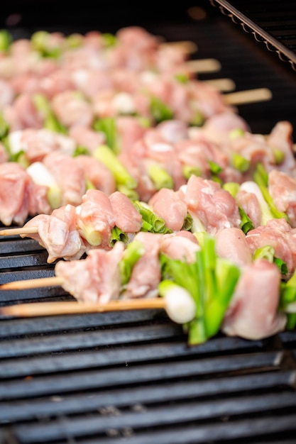 Passo dopo passo. Spiedini di yakitori di pollo crudo sulla griglia a gas all'aperto.