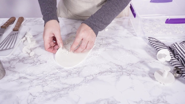 Passo dopo passo. Tagliare i fiocchi di neve con le formine per biscotti dal fondente bianco su un bancone di marmo.