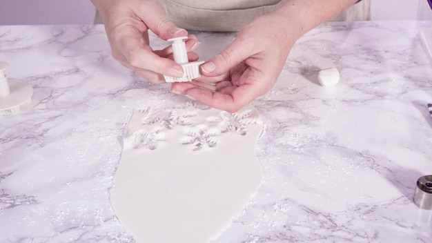 Passo dopo passo. Tagliare i fiocchi di neve con le formine per biscotti dal fondente bianco su un bancone di marmo.