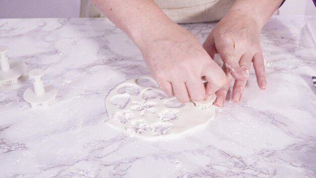 Passo dopo passo. Tagliare i fiocchi di neve con le formine per biscotti dal fondente bianco su un bancone di marmo.