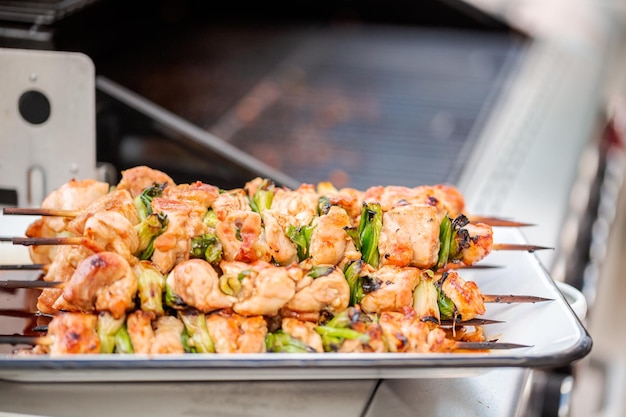 Passo dopo passo. Yakitori di pollo su un vassoio di metallo bianco accanto al grill a gas all'aperto.