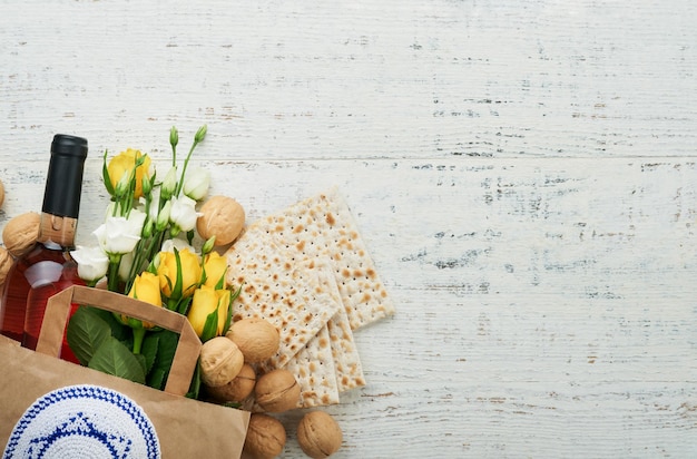 Passover Pesah celebrazione concetto Matzah kosher vino rosso noce e rose bianche e gialle Rituale tradizionale Pane ebraico su sabbia colore vecchio muro di piastrelle sfondo Pesach festa ebraica Vista dall'alto