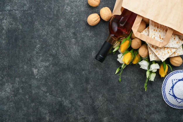 Passover Pesah celebrazione concetto Matzah kosher vino rosso noce e rose bianche e gialle Rituale tradizionale Pane ebraico su sabbia colore vecchio muro di piastrelle sfondo Pesach festa ebraica Vista dall'alto