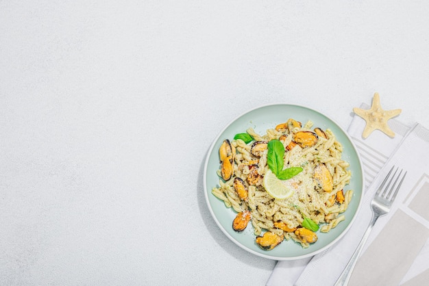 Pasta a base vegetale con pesto di cozze e parmigiano Cibo sano pronto da mangiare porzione servita su tavolo in pietra Vista dall'alto distesa piatta con ombra chiara e scura