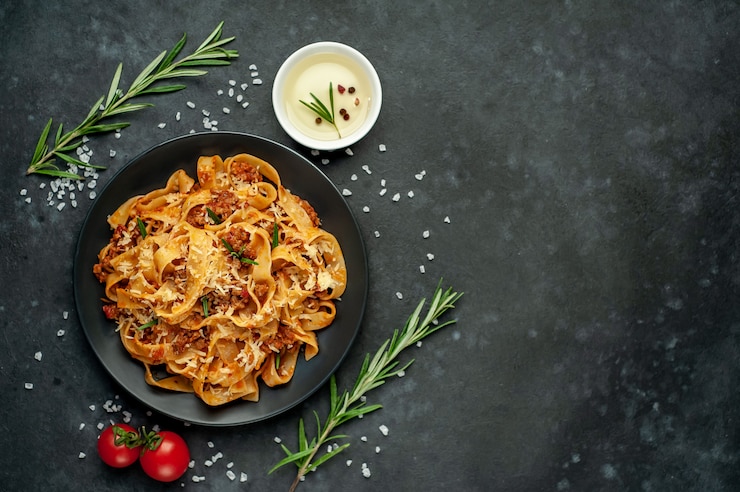 Foto pasta alla bolognese con spezie, piatto di pasta italiana con carne macinata e pomodori in un piatto scuro su uno sfondo di pietra